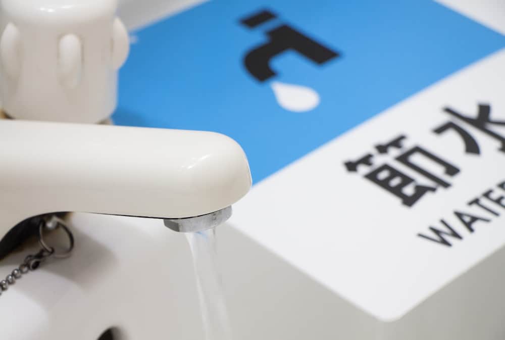 節水を呼び掛けるチラシと水を出しっぱなしの蛇口の写真