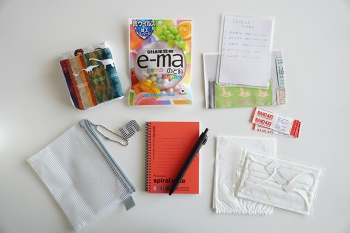 写真：小学生用の防災ポーチの中身　お菓子や身近な人の連絡先一覧、メモノート、ペンなどが入っている